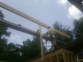 Carpenter setting a ridge beam over a new addition frame — Ice Dam Removal by Roofing Brothers in Helix
