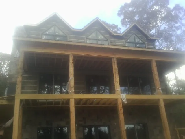 Dormers and porch framing on a large log home under construction — Roof Coating work by our crew in Helix
