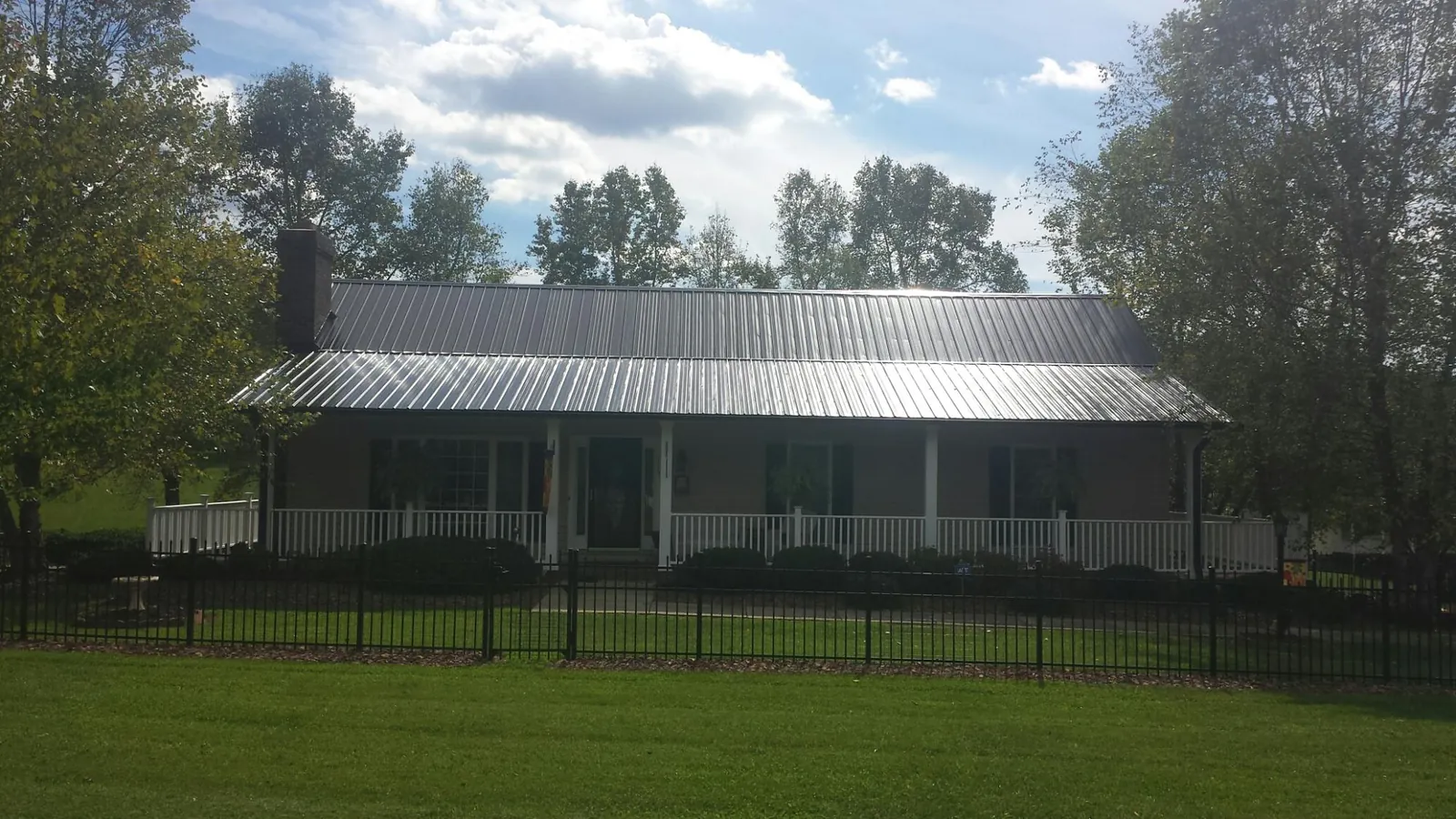 Gray metal roof on a brick ranch with a full width front porch — Gutter Guard Installation work by our crew in Helix