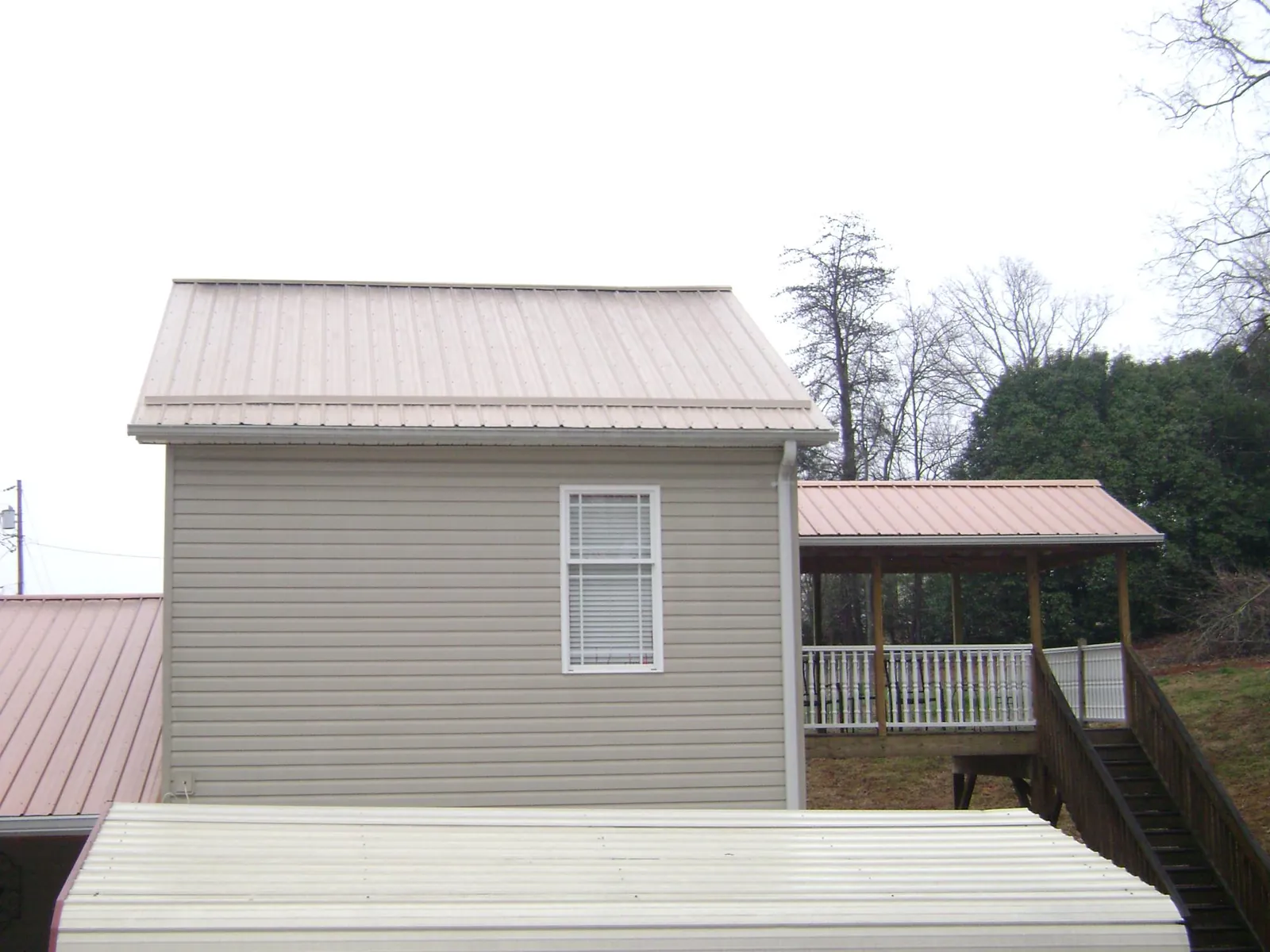 Tan metal roofs on a two story addition and attached porch, from a Roof Replacement job in Helix
